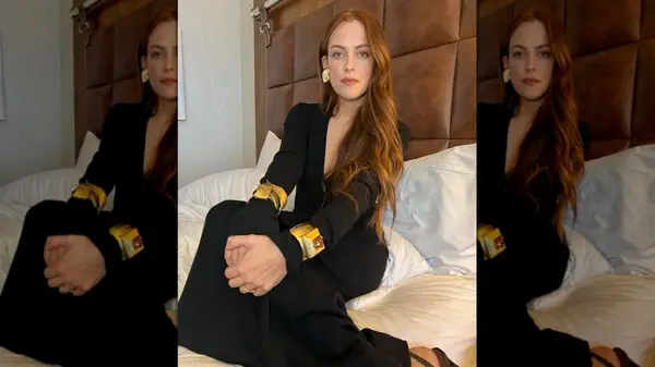 Riley Keough posing with her hands on her knees while sitting on a bed
