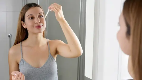 Woman applying serum on face