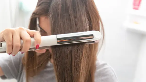 Person using straightener on hair