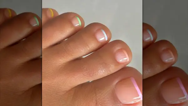 A close-up of a classic French pedicure but with different colored tips by Milly Mason