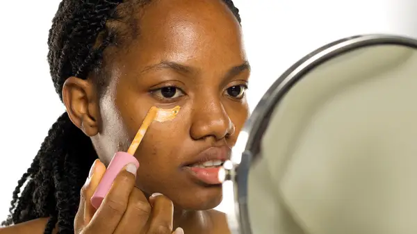 Woman applying concealer under eye