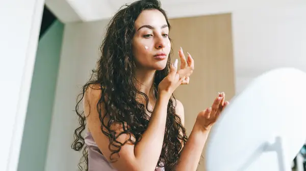 woman applying cream to under eyes