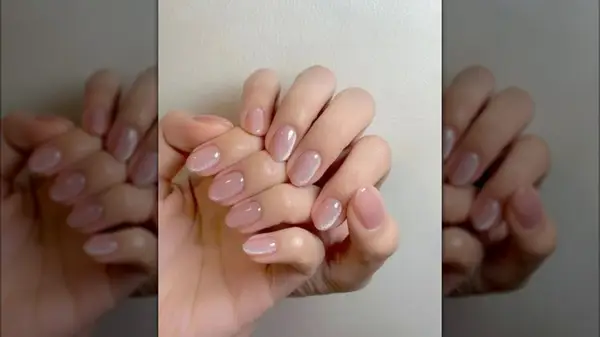 Hands with a pale pink cat eye manicure