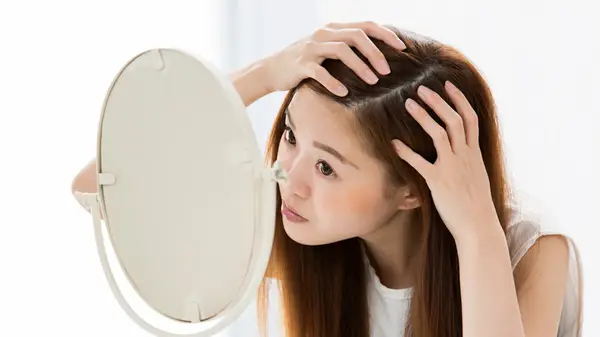 woman looking at scalp in mirror