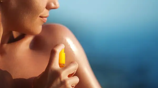 Woman spraying sunscreen