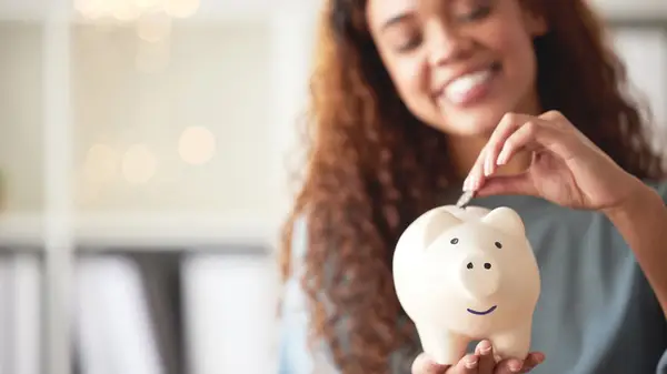 Woman putting money in piggy bank