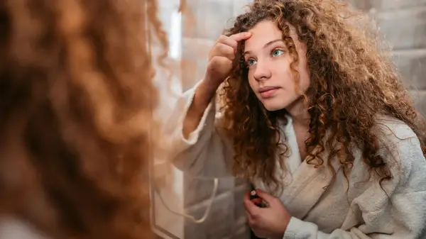 Woman touching face in mirror