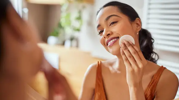 Woman cleans her face with cotton pad