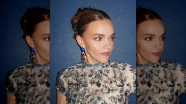 Madeline Brewer wearing a blue dress with a blue wall behind her
