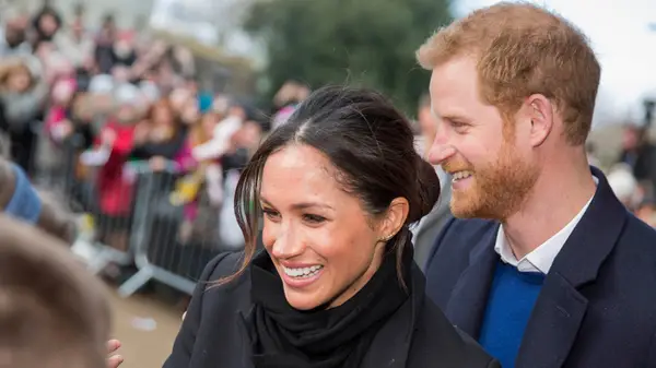 Meghan Markle greeting fans with Prince Harry standing behind her