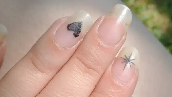 Heart and starburst fingernail tattoos, slightly grown out