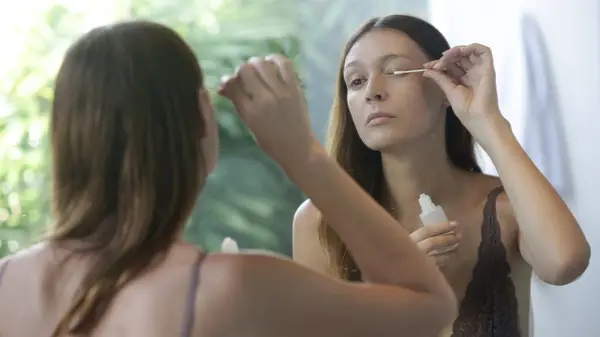A woman applying lash serum