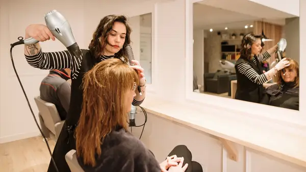 Woman blow-drying a client