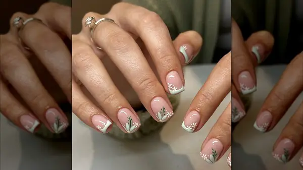 A French manicure with white and green botanical details