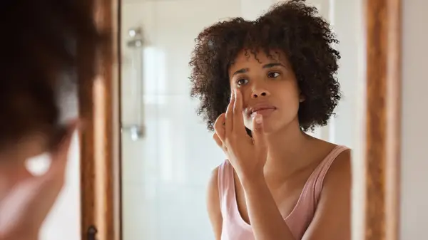 Woman applying skincare in the mirror