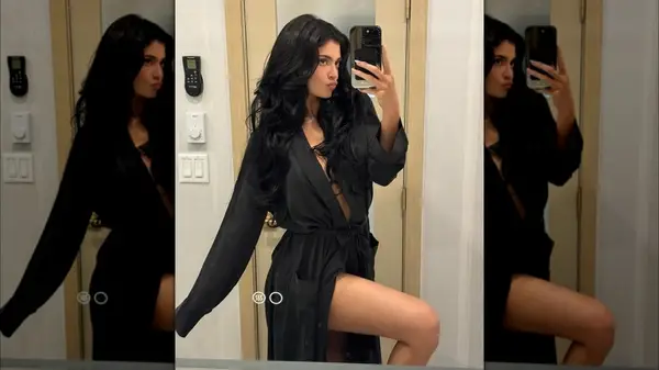 Kylie Jenner posing for a mirror selfie while making a kissy face and wearing a black robe