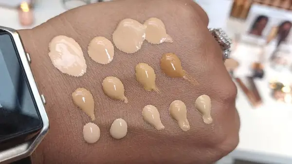 Hand with 13 different foundation swatches