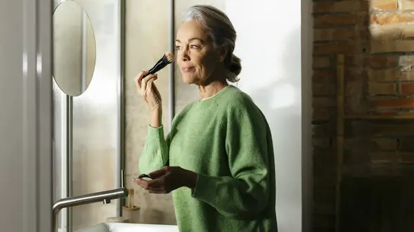 A woman applying foundation with a brush
