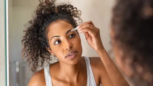 Woman tweezing eyebrows