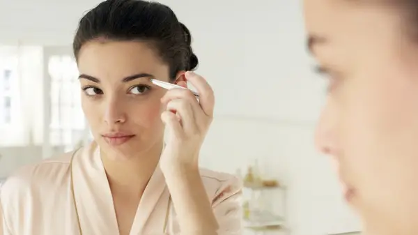 Woman pencilling in her eyebrows