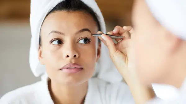 Woman plucking her eyebrows
