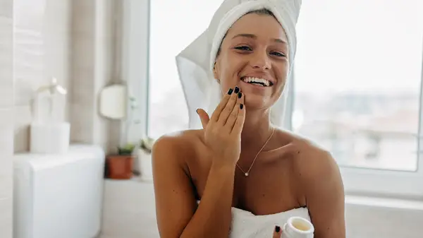 Woman applying moisturizer to face 