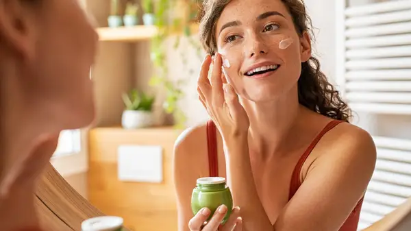 Young woman applying moisturizer
