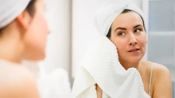 Woman drying face with clean towel