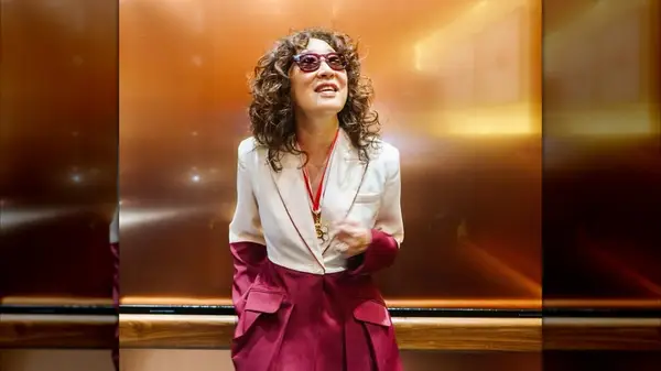 Sandra Oh standing in an elevator with curly, shoulder-length hair