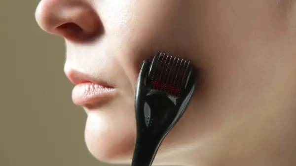 A woman derma rolling her face
