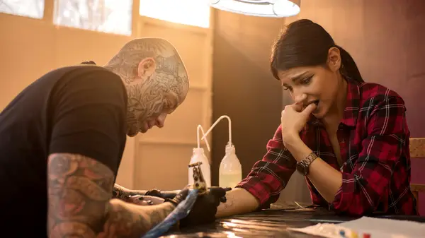 woman getting a tattoo looking nervous