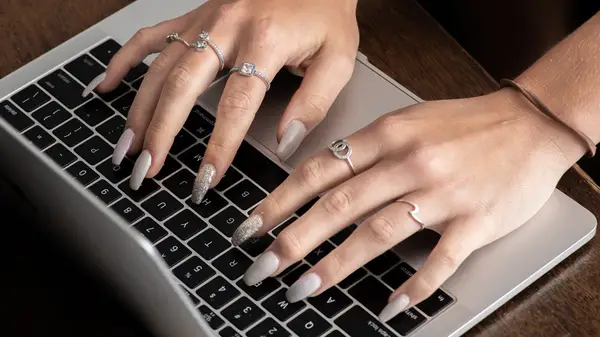 Long nails typing on laptop