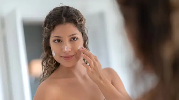 Woman applying sunscreen in bathroom