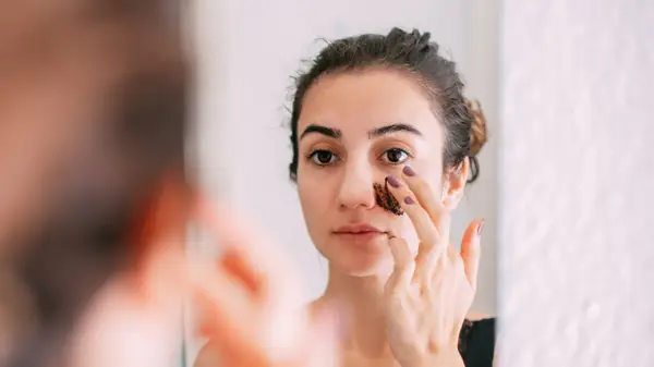 Woman applying exfoliator on face