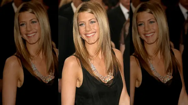 Jennifer Aniston smiling with bronzy, straight hair parted to the side with ear-tucked bangs