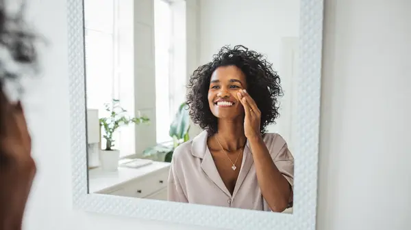 A woman admiring skin in mirror