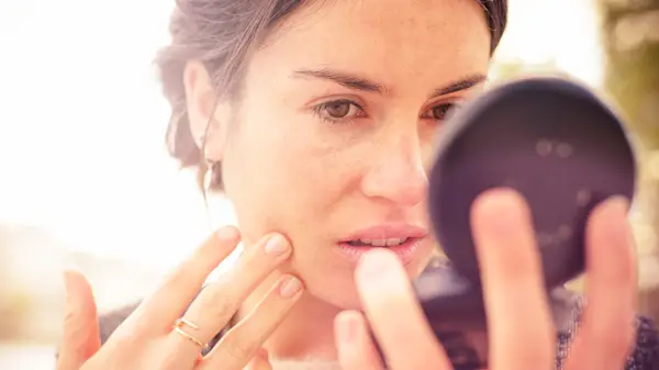 woman holding a compact mirror