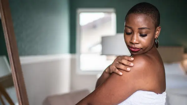 Woman moisturizing her shoulder 