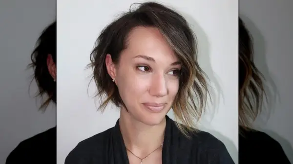 A woman on a white background with a softly curled asymmetrical bob haircut