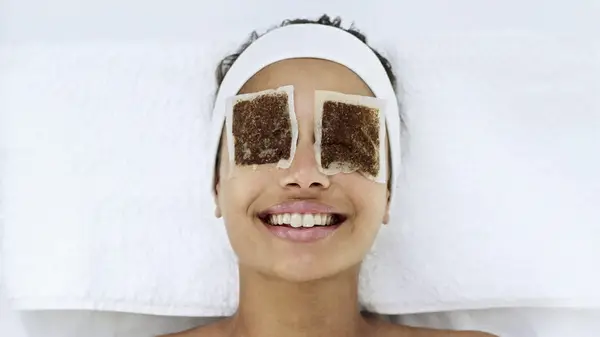 Woman with tea bags over her eyes