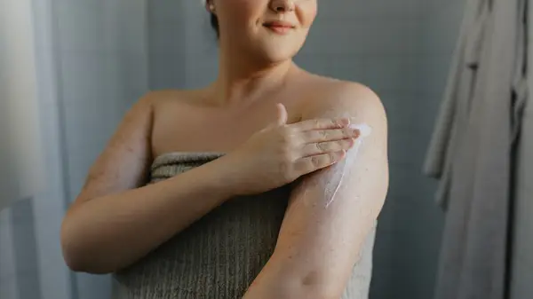 woman applies moisturizer