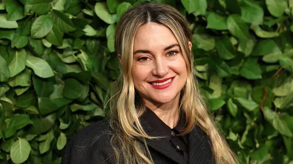 Shailene Woodley smiling a film festival event in front of a foliage background
