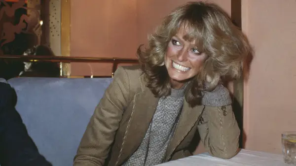 Farrah Fawcett sitting at table