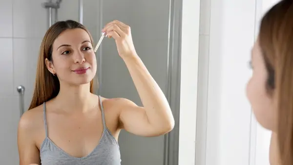 woman applying face serum
