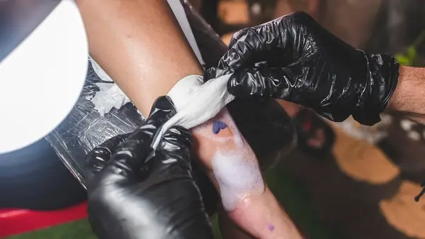 Artist cleaning and applying a cloth to a small heart tattoo
