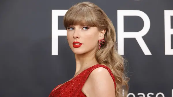 Taylor Swift looking to the slide while posing in red at the Grammys