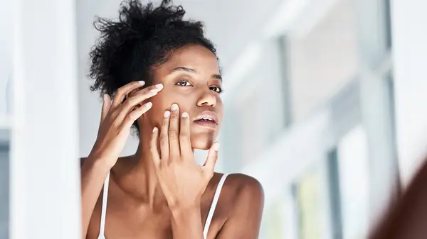 Woman looking at her skin in the mirror