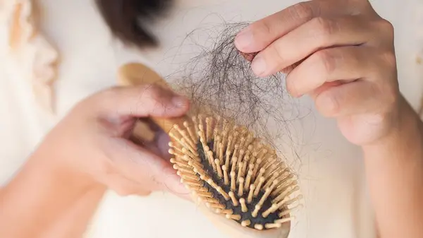 Woman picking hairs from brush