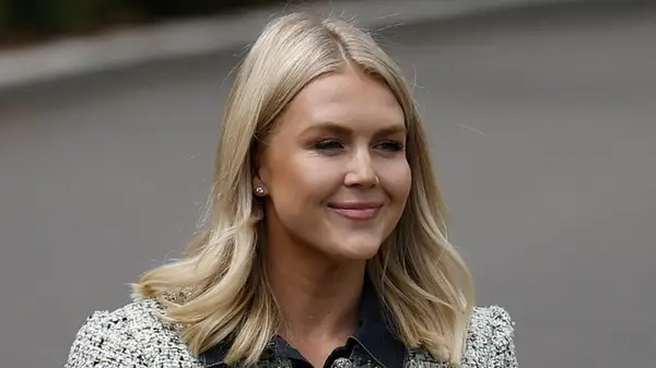 Karoline Leavitt smiling while being photographed outdoors