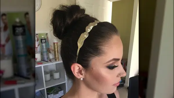 A woman with a headband and a bun 